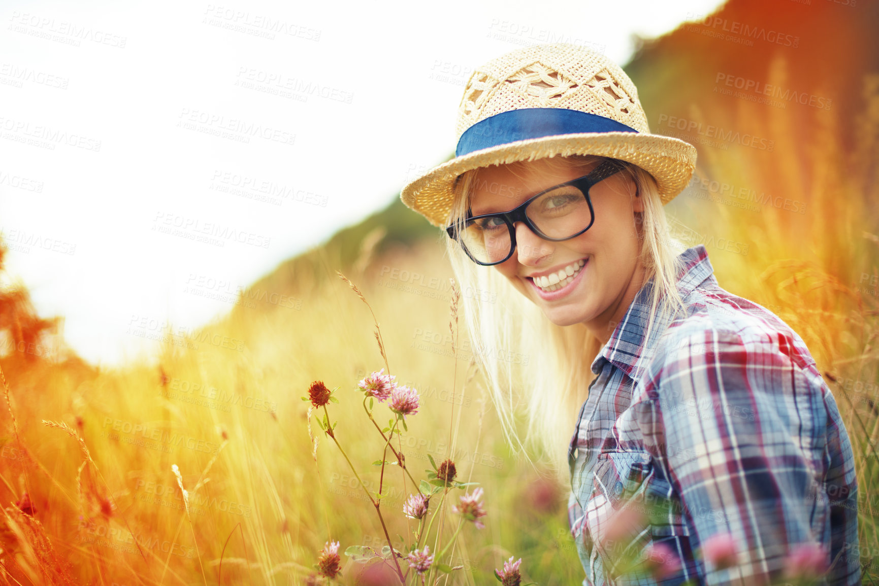 Buy stock photo Lens flare, countryside and portrait of woman with flowers in field for freedom, wellness and fresh air outdoors. Nature, summer and happy female person in natural meadow for relaxing, calm and peace