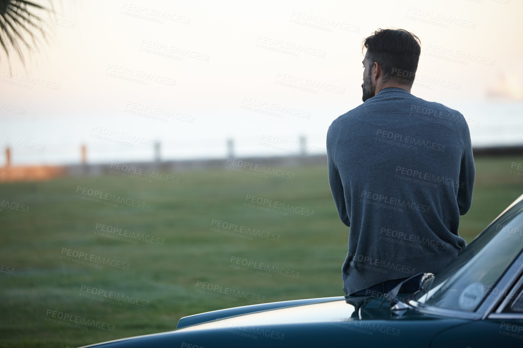 Buy stock photo Rearview shot of a man looking at the view while leaning against his car