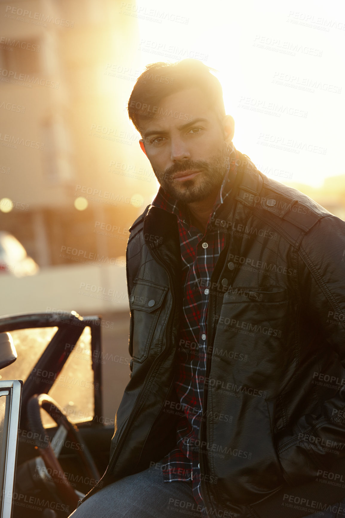 Buy stock photo Shot of a young man sitting on his car