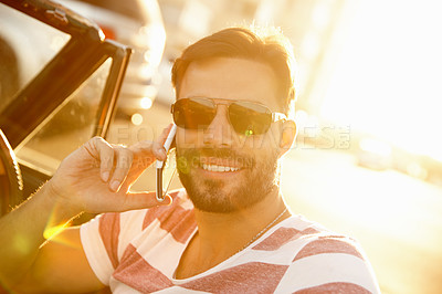 Buy stock photo Shot of a young man sitting in his car while talking on his cellphone