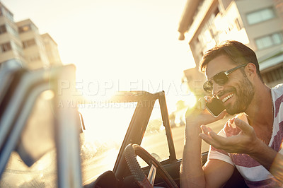 Buy stock photo Shot of a young man sitting in his car while talking on his cellphone