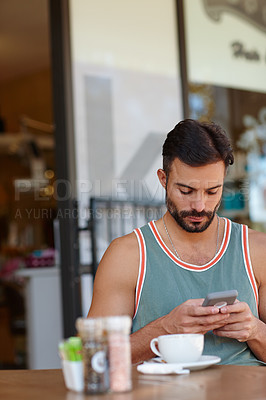 Buy stock photo A young man sitting in a coffee shop while texting