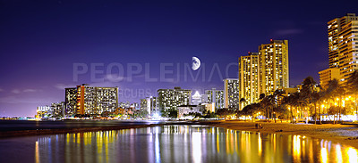 Buy stock photo Night, city and coastal with lights, moon and journey with vacation, holiday and getaway trip. Waikiki, urban town and buildings with reflections, water and seaside with adventure or destination spot