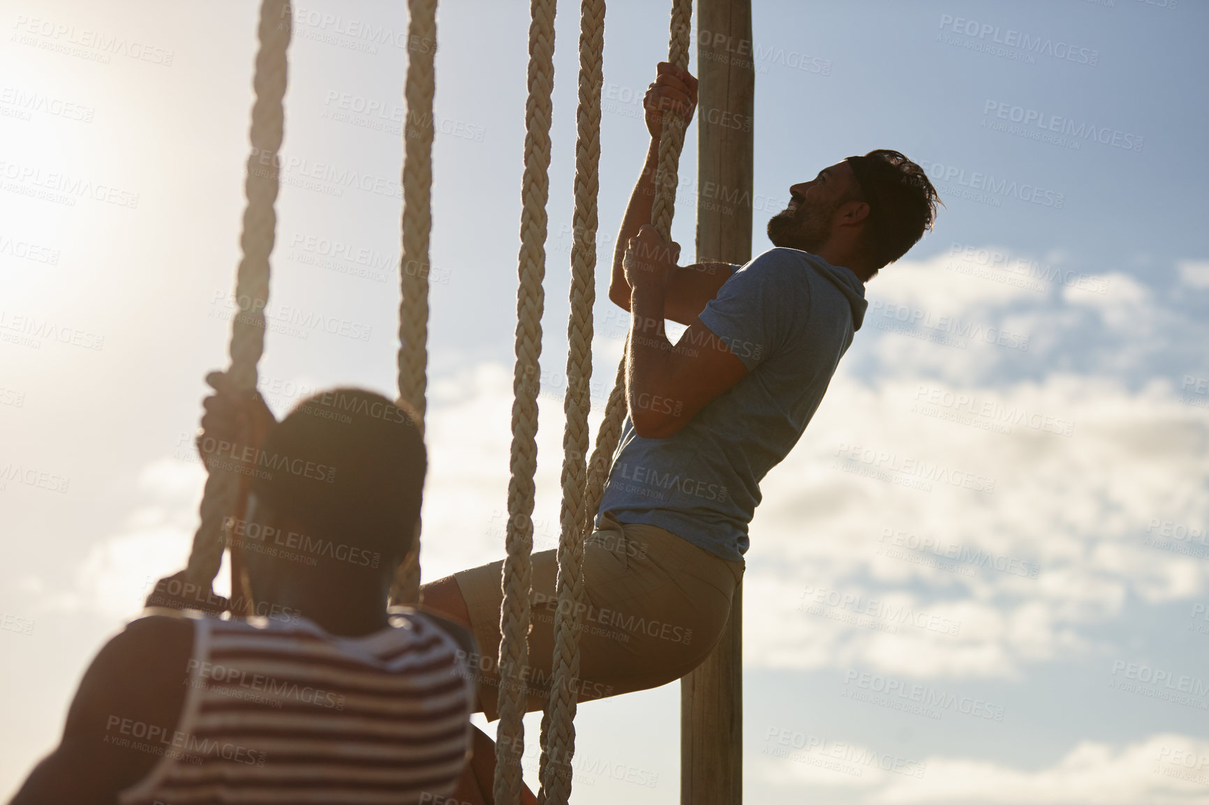 Buy stock photo Shot of two young men climbing up ropes at a military bootcamp