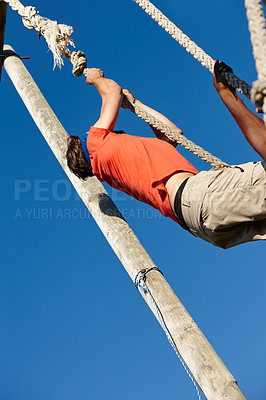 Buy stock photo Shot of a man climbing up a rope at bootcamp