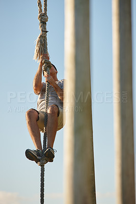 Buy stock photo Shot of a young man climbing up a rope at a military bootcamp