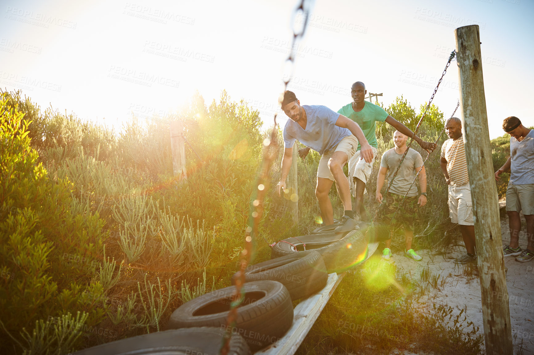 Buy stock photo Shot of a group of men going through an obstacle course at bootcamp