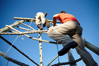Buy stock photo Shot of two young men going through an obstacle course at bootcamp