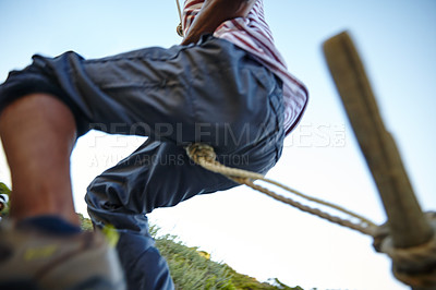 Buy stock photo Cropped shot of a man swinging on a rope at bootcamp