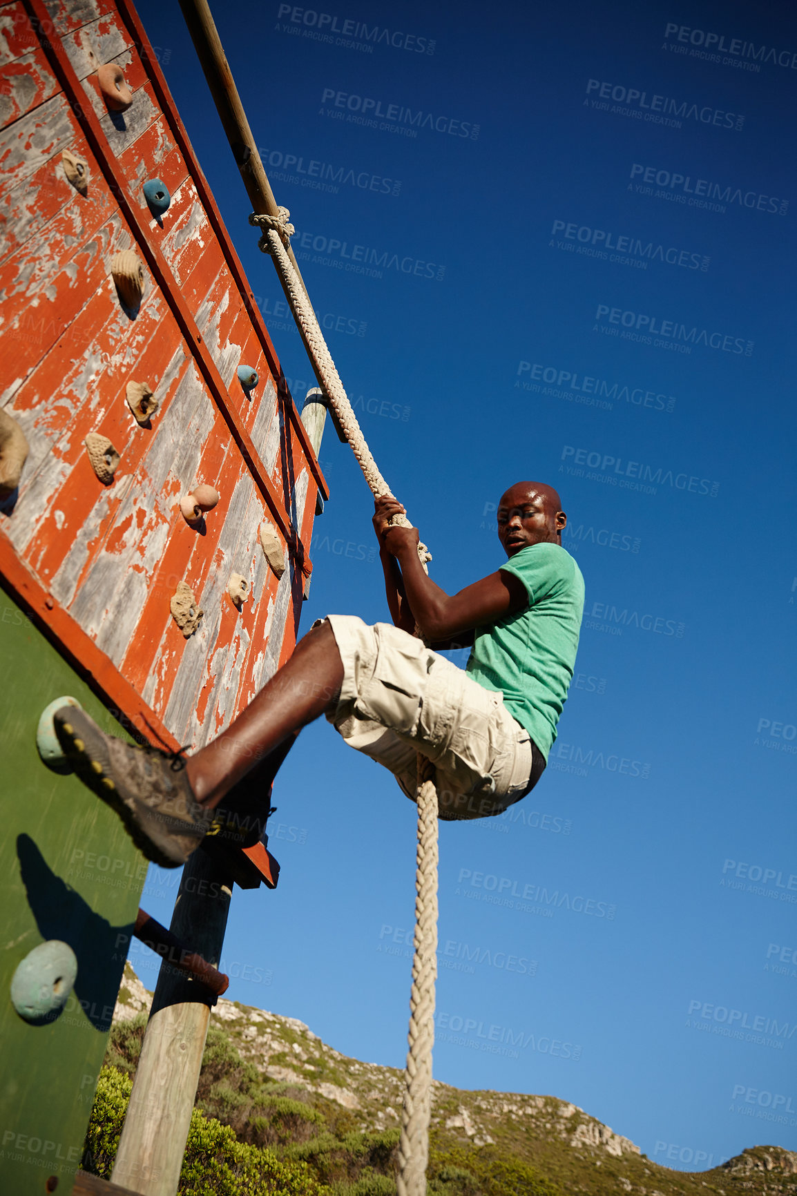 Buy stock photo Shot of a young man climbing over an obstacle at military bootcamp