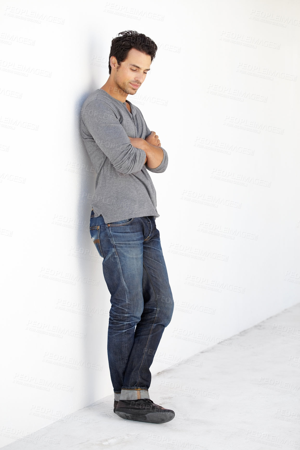Buy stock photo Full length shot of a handsome young man leaning against a white wall outside