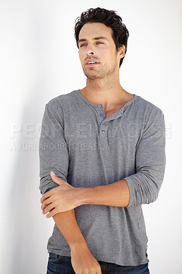 Buy stock photo Shot of a handsome young man standing outside and looking away thoughtfully