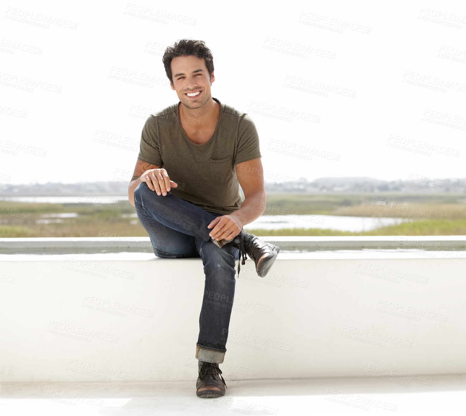 Buy stock photo Portrait of a handsome young man sitting on the roof of a building