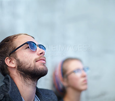Buy stock photo Thinking, man and city with sunglasses for relax, peace and idea outdoor against wall with eyewear. Couple, people and thoughtful with memory, remember and leaning with shades and casual smile