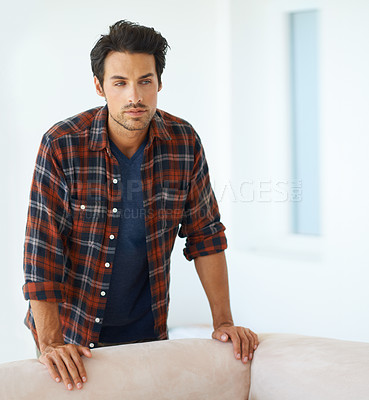 Buy stock photo Man, thinking and serious by sofa for idea, question and contemplating in living room of apartment or home. Person, face and thoughtful or calm by couch in lounge for chill, rest and shirt on weekend