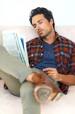 Buy stock photo Man, relax and reading a newspaper on couch in home, living room and learning about event from media. Calm, weekend and person with news, paper or article on sofa in apartment with information