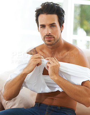 Buy stock photo Portrait, man and take off tshirt on sofa for comfort, rest or chilling on weekend, day off or vacation. Sweater, removal or face of male person in living room undressing, relax or confident at home