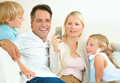 Buy stock photo Family, face or happy on sofa with phone for social media, streaming or internet video with relax, peace and love. Parents, kids or smile with smartphone on couch of lounge with care or break in home
