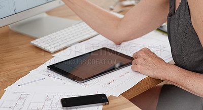 Buy stock photo A female architect working on building plans using her digital tablet and computer