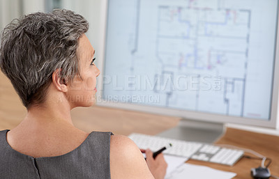 Buy stock photo A mature female architect working on building plans on her touchscreen computer