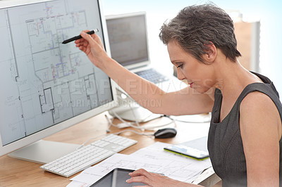 Buy stock photo A mature female architect working on building plans on her touchscreen computer