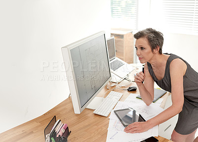 Buy stock photo A mature female architect working on building plans in her office