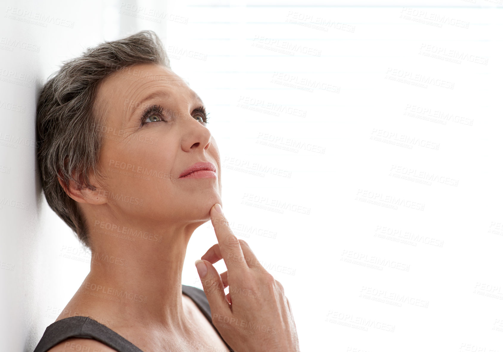 Buy stock photo A mature businesswoman looking up thoughtfully while leaning against a wall