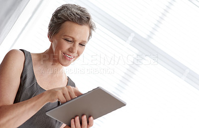 Buy stock photo A mature businesswoman working on her digital tablet at the office