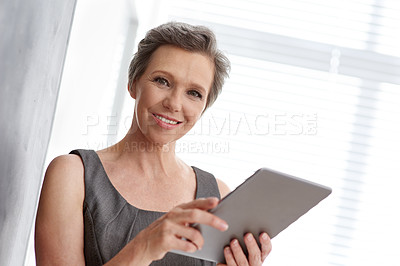 Buy stock photo A mature businesswoman working on her digital tablet at the office