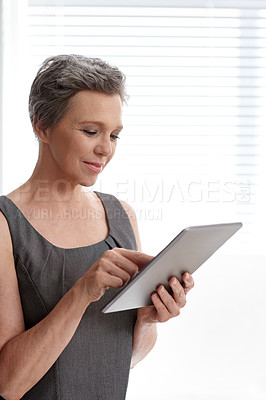 Buy stock photo A mature businesswoman working on her digital tablet at the office