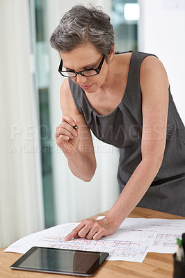 Buy stock photo Woman, architect and blueprint in office, document or review with reading, property or renovation project. Mature person, floor plan or touchscreen for design, sketch and development for real estate