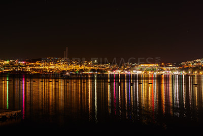 Buy stock photo City lights reflecting on water with dark sky copy space. River or lake at night with beach house light reflections on water surface. Colorful midnight skyscraper glowing in still water near a harbor