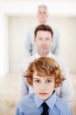 Buy stock photo Cropped portrait of a young boy standing with his father and grandfather