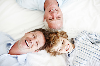 Buy stock photo High angle portrait of a handsome man lying on the bed with his son and father