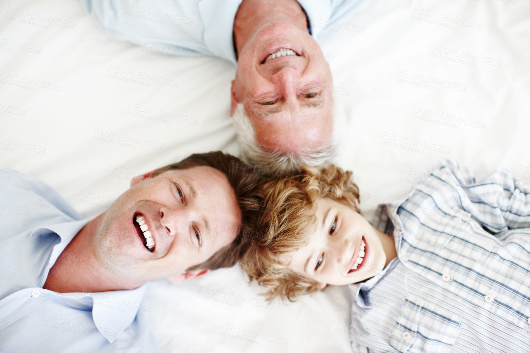 Buy stock photo High angle portrait of a handsome man lying on the bed with his son and father