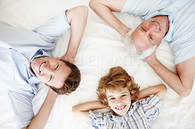 Buy stock photo High angle portrait of a handsome man lying on the bed with his son and father