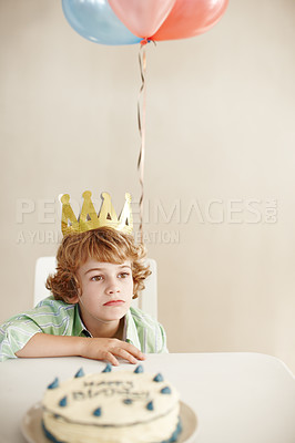Buy stock photo Birthday party, cake and balloons with sad boy by table in family home for celebration, growth and lonely. Dessert, decoration and sweet pastry for event, waiting and thinking with crown in house