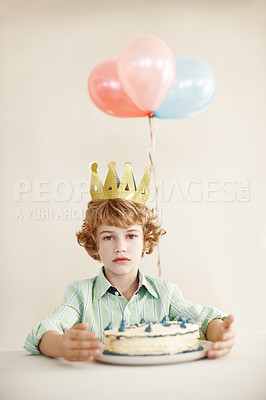 Buy stock photo Birthday cake, portrait and balloons with sad boy by table in family home for celebration, growth and lonely. Dessert, decoration and sweet pastry for event, serious and milestone with crown in house