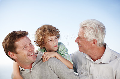 Buy stock photo Grandfather, father and child by blue sky with smile for bonding, relationship and relax together. Family, generations and grandpa, dad and young boy on shoulders for holiday, vacation and weekend