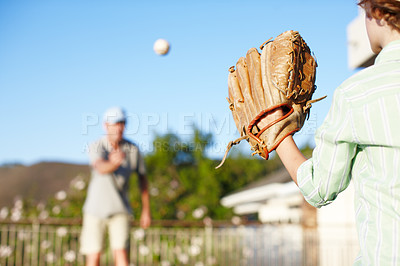 Buy stock photo Cropped shot of a father and son throwing the baseball outdoors in the yard