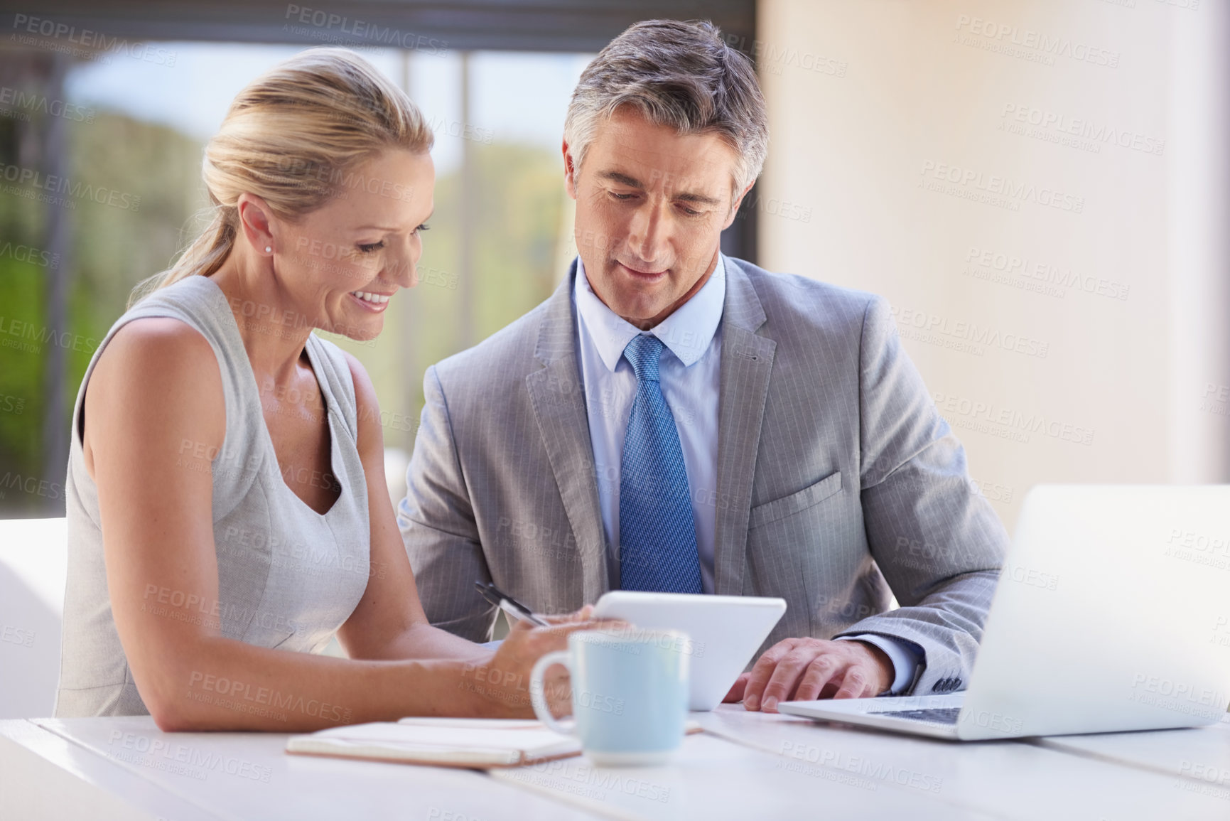 Buy stock photo Cropped shot of two colleagues working together at a desk