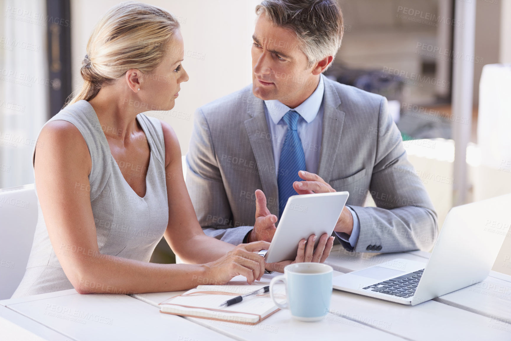 Buy stock photo Cropped shot of two colleagues working together at a desk