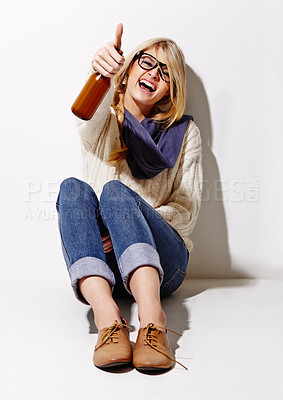Buy stock photo Full length studio portrait of a young woman having a beer while leaning against a wall