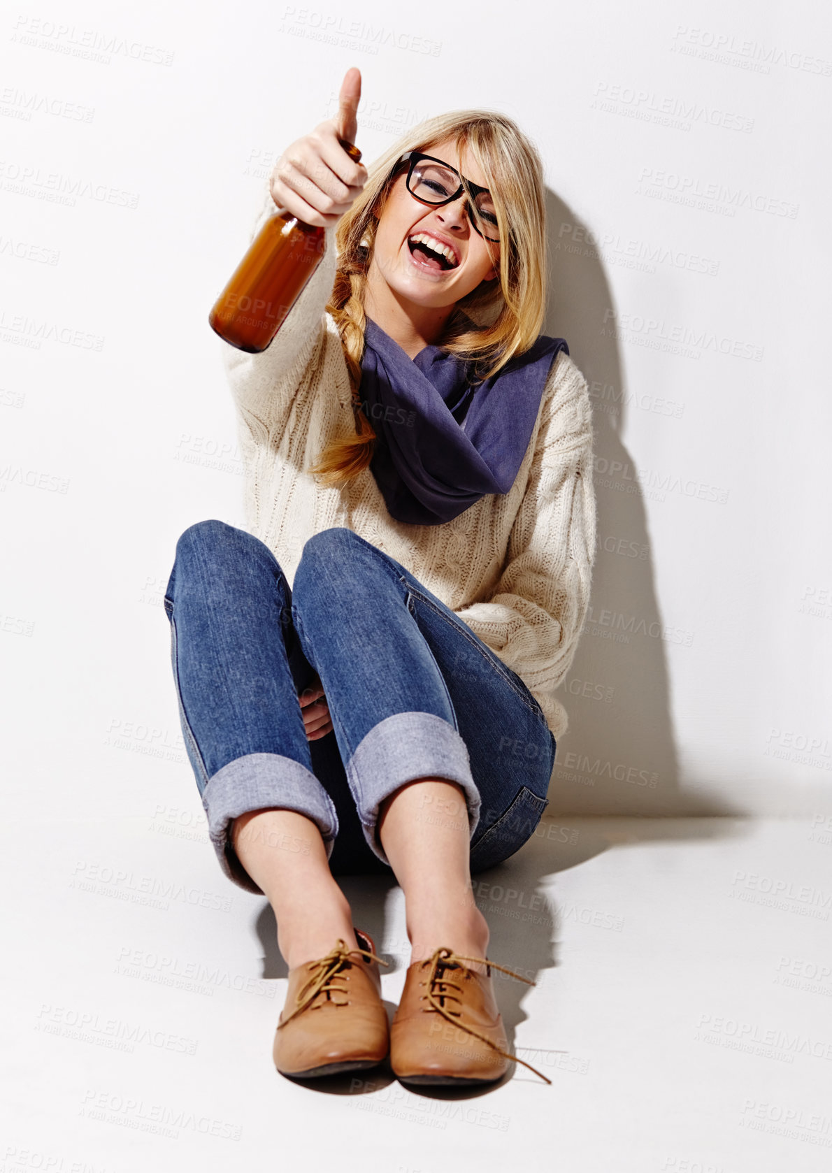 Buy stock photo Full length studio portrait of a young woman having a beer while leaning against a wall