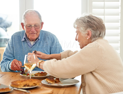 Buy stock photo Love, help and senior couple eating lunch together in the dining room of their modern home. Happy, date and elderly man and woman in retirement talking, bonding and enjoying meal or food in a house.