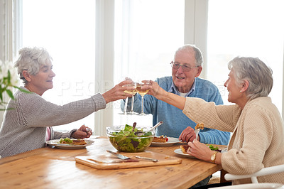 Buy stock photo Wine, cheers and senior friends at brunch in home with smile, celebration and bonding in retirement. Food, drinks and toast with glass, old man and women at dinner table together for happy lunch.