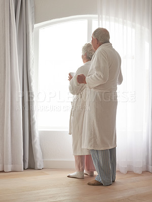 Buy stock photo Senior couple, hug and coffee by window in retirement, love and bonding in bathrobes on holiday. Elderly people, back and embracing for affection in marriage, hot beverage and morning routine at home