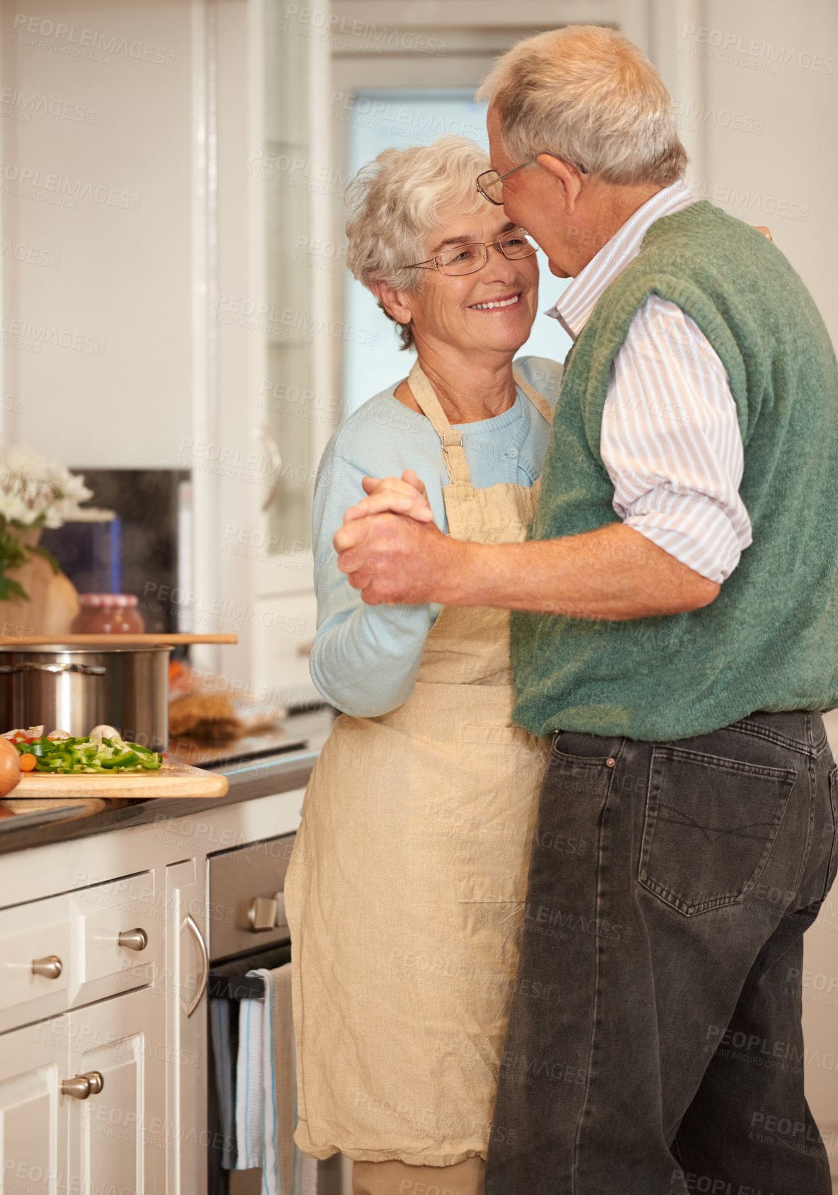 Buy stock photo Shot of a senior couple enjoying a playful moment together in the kitchen