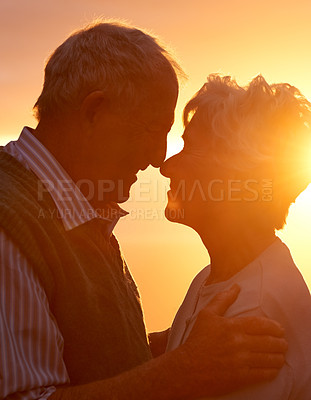 Buy stock photo Sunset, elderly couple and embrace outdoor, love and bonding for connection together in nature. Man, woman and touch forehead for care, romance or support for commitment to relationship in retirement