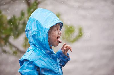 Buy stock photo Boy, rain jacket and playing in winter with happiness, fun and carefree childhood in cold weather. Young child, tongue out and water in nature for vacation, holiday and weekend enjoyment in Australia